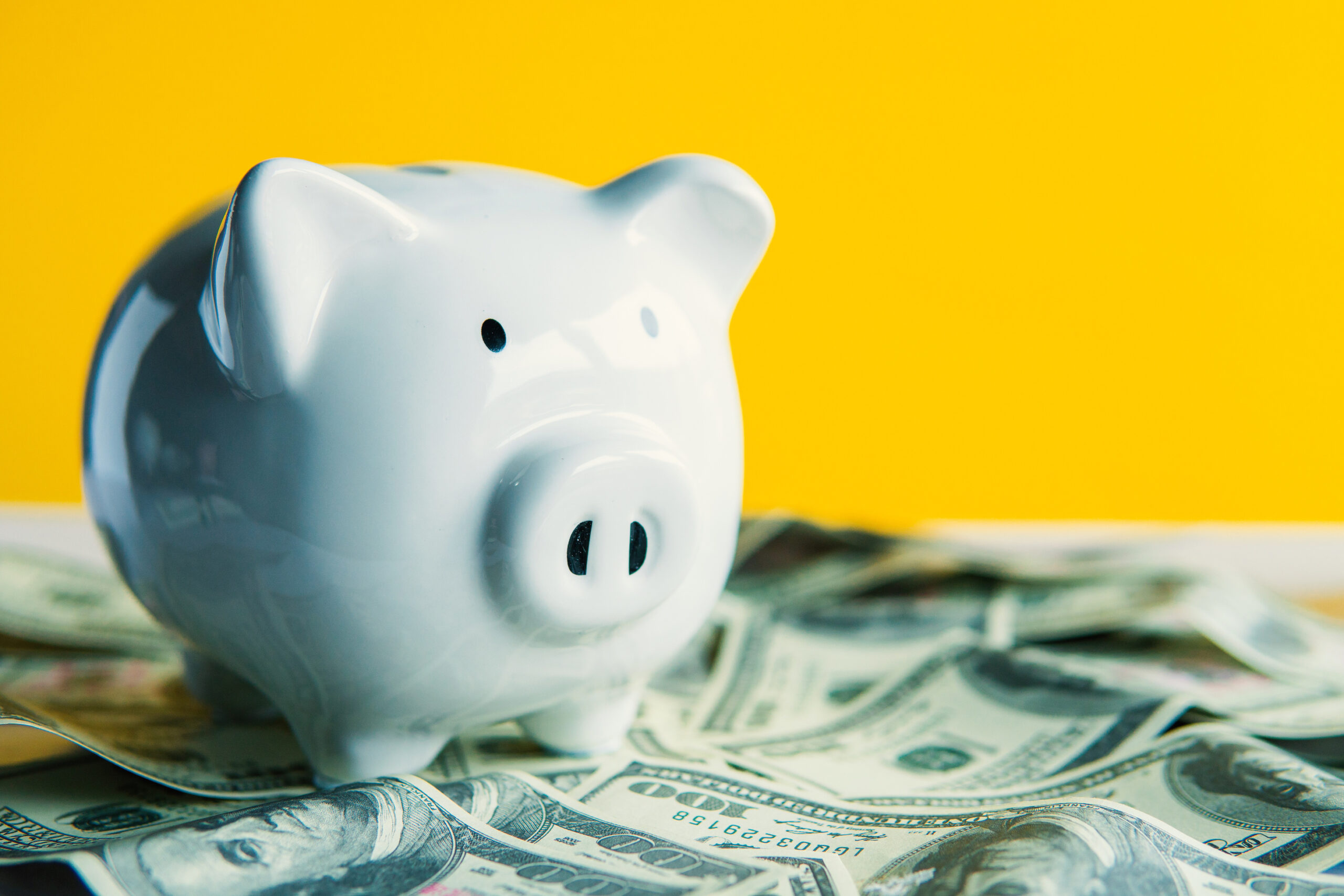 White piggy bank on the table and yellow background save money