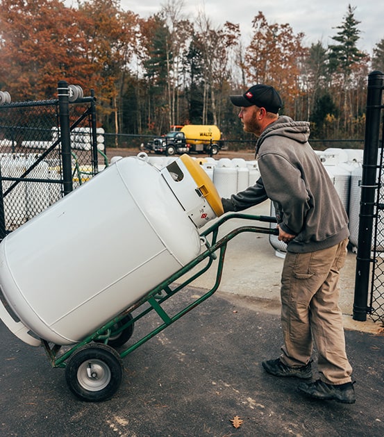 waltz employee moving propane tank with a hand cart
